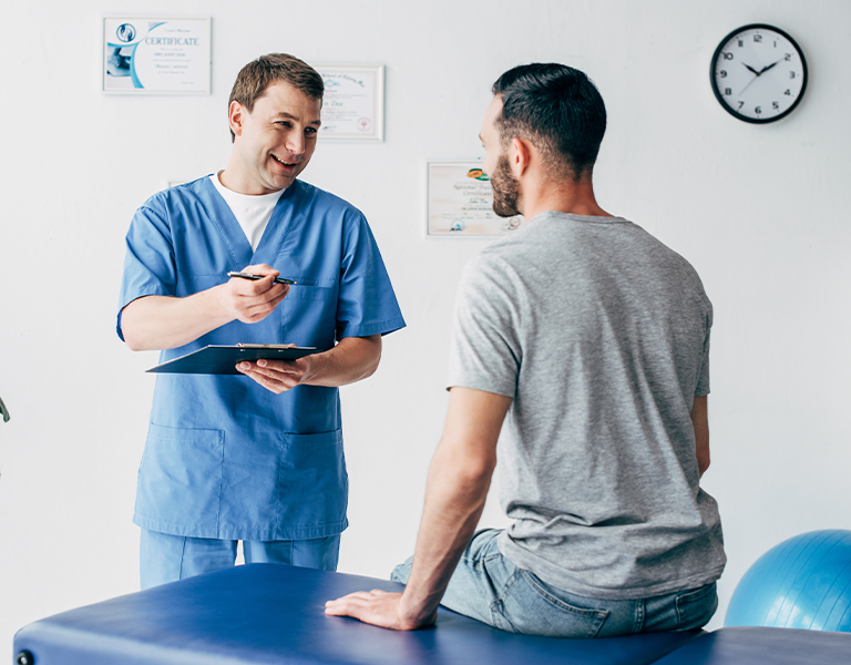 Paciente de usando uma camiseta cinza escutando, atentamente, as recomendações passadas pelo médico